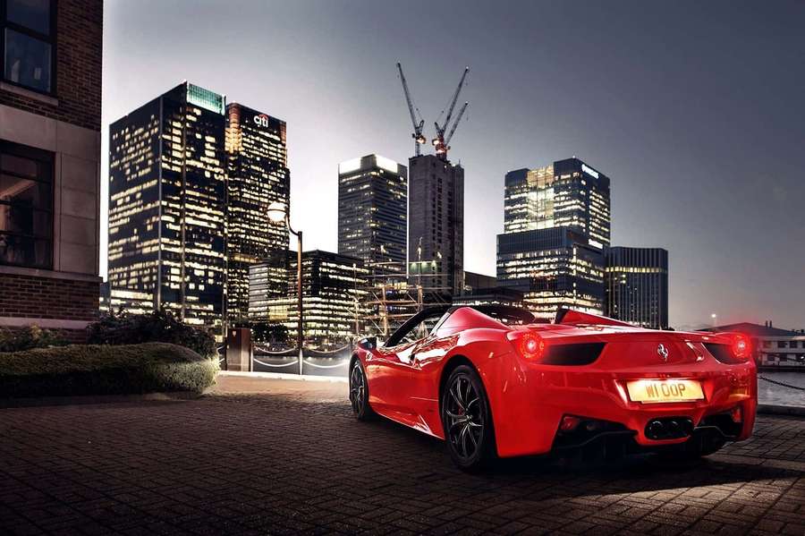 Red Ferrari parked in city at dusk with lit skyscrapers behind. — Ferrari 458 Spider Wallpaper