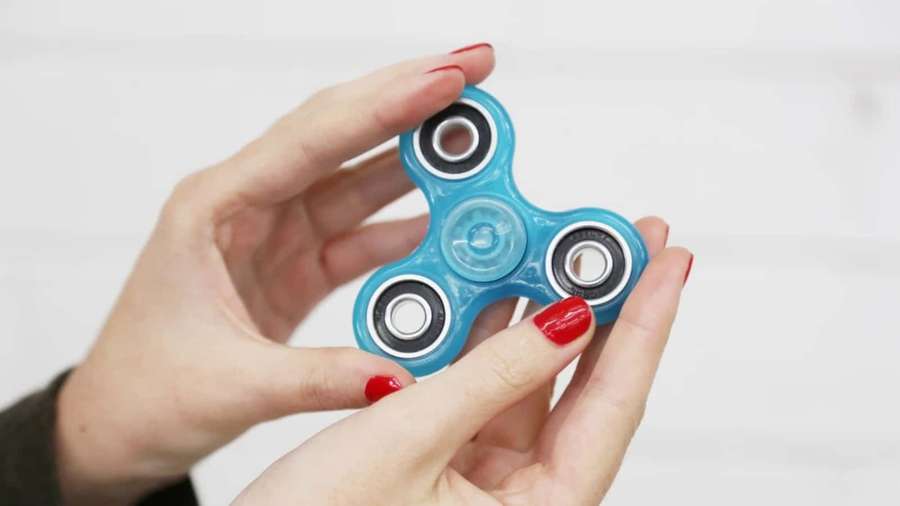 Hand holding a blue fidget spinner with red nail polish. — Fidget Picture