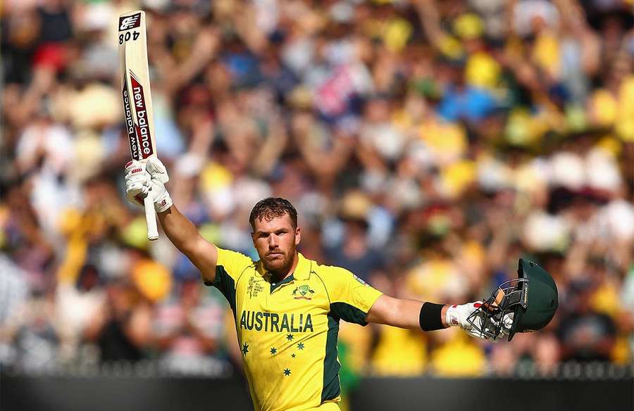 Cricket player in yellow jersey celebrates with bat and helmet raised. — Finch Wallpaper