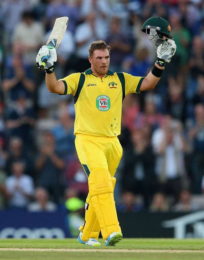 Cricketspieler in gelber Uniform feiert mit erhobenem Schläger und Helm. — Fink Wallpaper