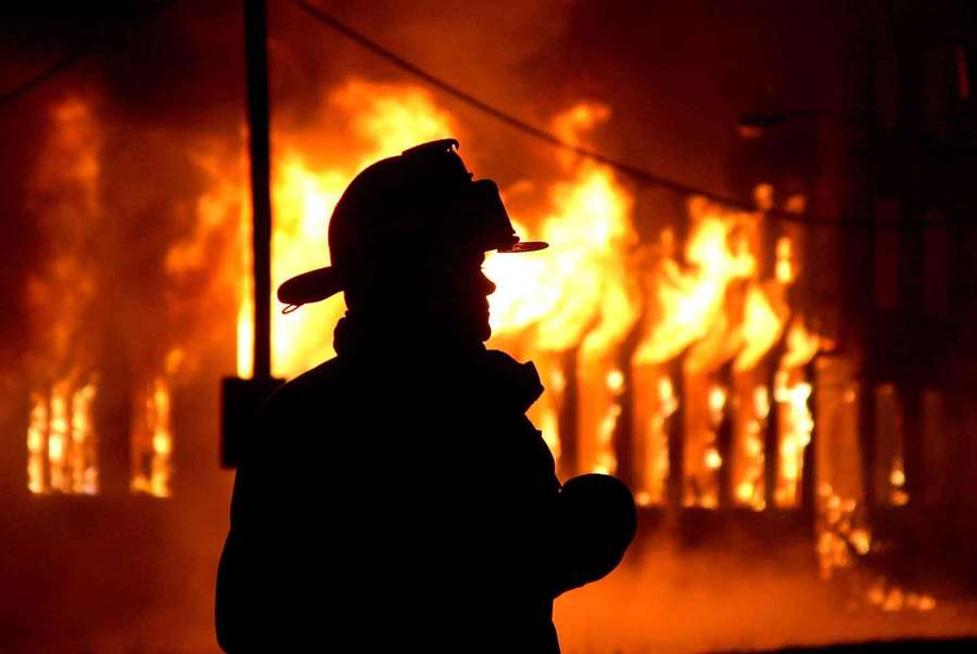 Firefighter silhouette against burning building at night. — Firefighter Background