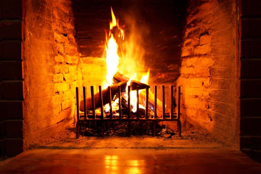 A crackling wood fire in a stone fireplace casting golden light — Fireplace Zoom Background