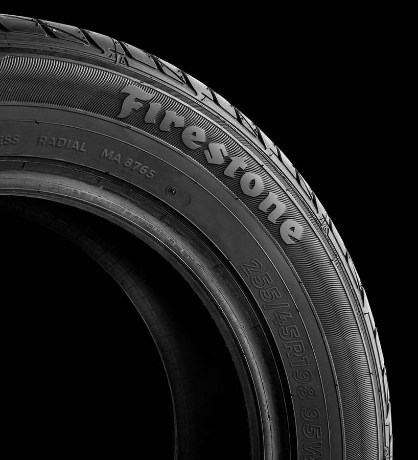 Close-up of a Firestone tire tread with visible text and grooves against black background. — Firestone Wallpaper