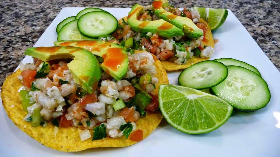 Zwei Tostadas mit Ceviche, Avocado, Limette und Gurkenscheiben auf einem weißen Teller. — Fisch Und Chips Wallpaper