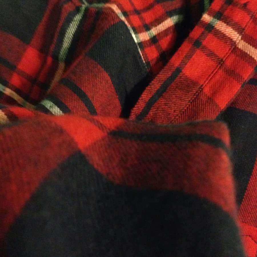 Close-up of red black and green plaid flannel fabric with texture and folds. — Flannel Background