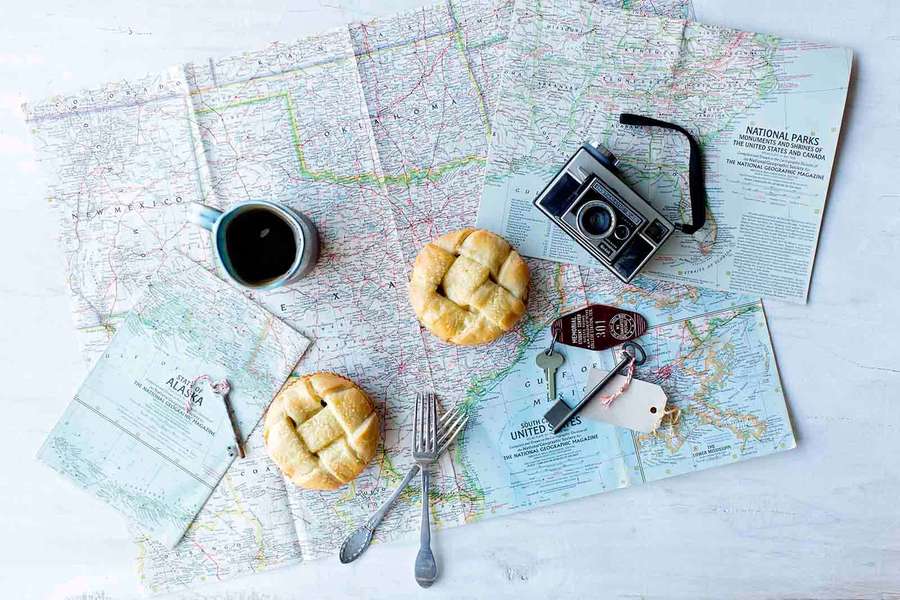 Travel-themed flat lay with maps coffee pastries and camera on white wood. — Flat Lay Background