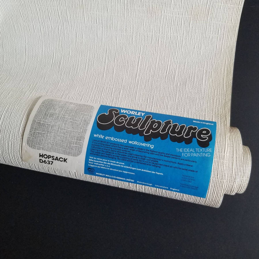 Rolo de papel de parede texturizado branco com etiqueta azul em fundo escuro. — Flexível Papéis de Parede