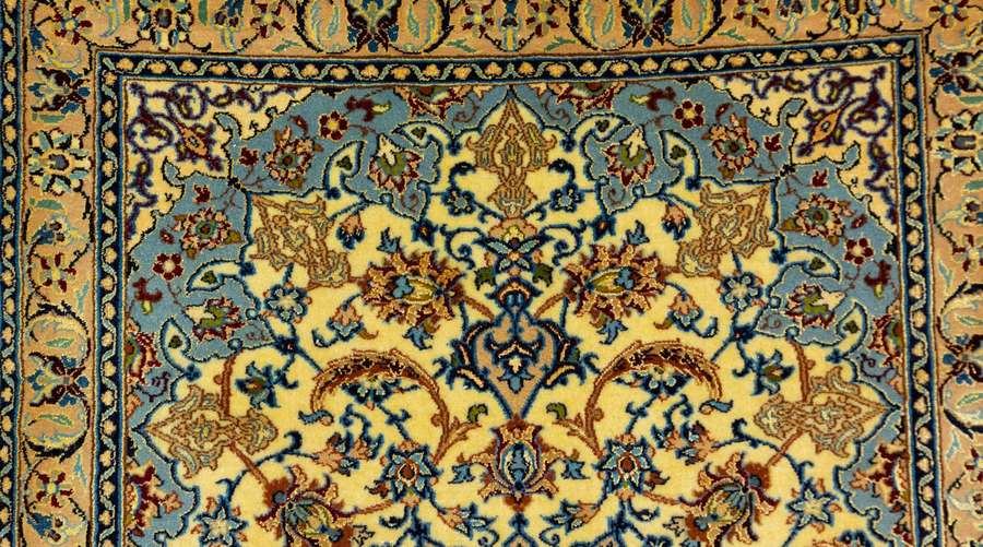 Close-up of a detailed Persian rug with blue gold and cream patterns. — Floral Pattern Wallpaper