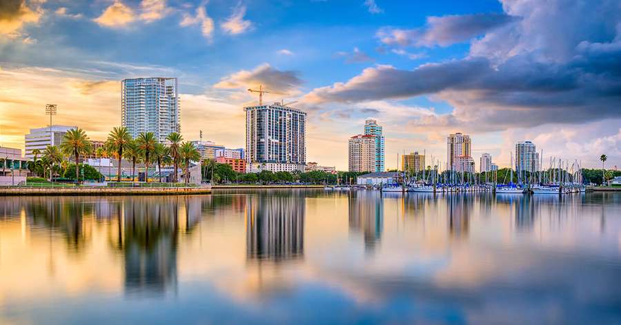 Kaupungin siluetti auringonlaskussa palmujen ja purjeveneiden kanssa heijastuen tyynessä vedessä. — Florida Ranta Taustakuvat