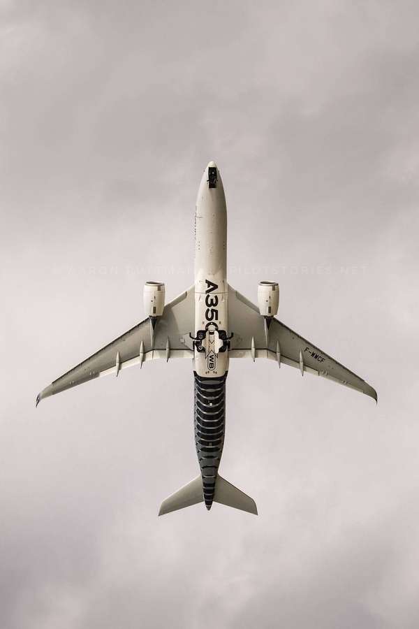 Airbus A350 Flugzeug von unten gegen einen bewölkten Himmel gesehen. — Flugzeug Android Wallpaper