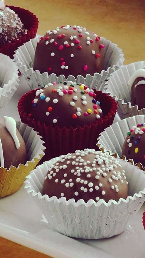 Brillantes trufas de chocolate con chispas de colores en capacillos de papel decorativos. — Fondods de Postres de Android Fondos