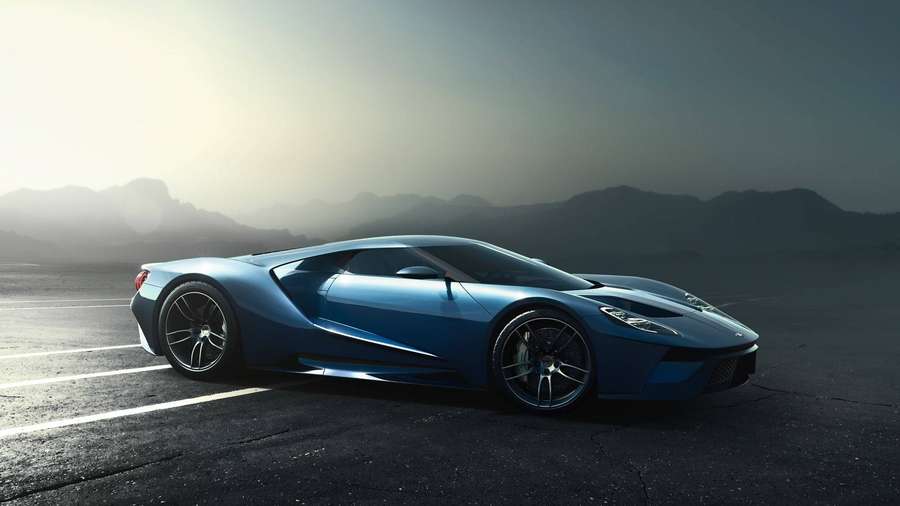 Blue sports car parked on asphalt with mountain backdrop at sunset. — Ford Gt Background