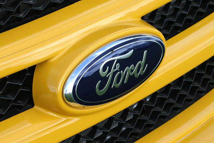 Close-up of Ford logo on yellow car grille — Ford Logo Wallpaper