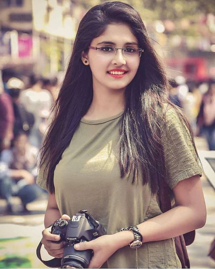 Junge Frau mit Brille hält eine Kamera auf einer belebten Straße. — Fotograf Wallpaper