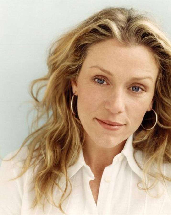 Woman with blonde hair and blue eyes wearing a white shirt and hoop earrings. — Frances mcdormand Wallpaper