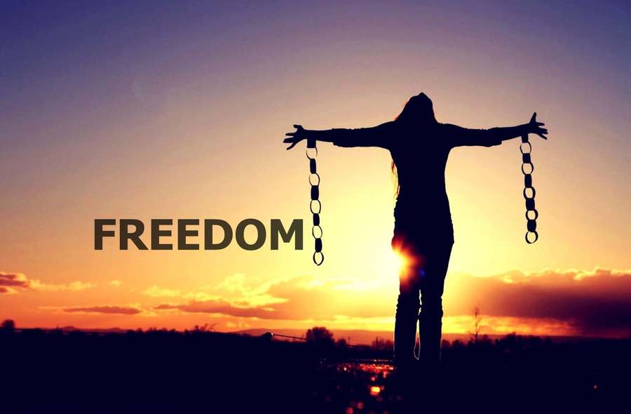 Person breaking chains at sunset with word freedom overlaid — Freedom Background
