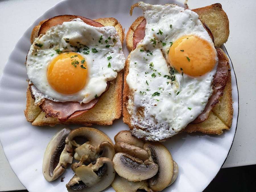 Dos huevos fritos sobre jamón y tostadas con champiñones salteados en un plato. — Fresco Fondos de pantalla