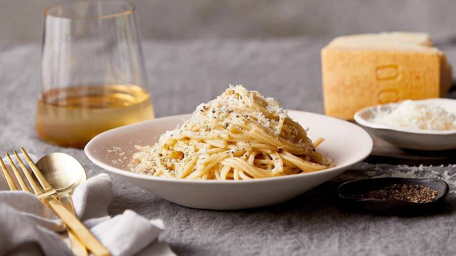 Cremige Spaghetti mit geriebenem Käse und schwarzem Pfeffer, serviert mit Wein und Parmesan. — Frisch Wallpaper