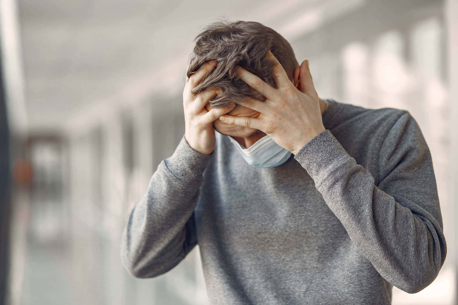 Mann med ansiktsmaske dekker ansiktet med hendene i gang — Frustrert Bakgrunner