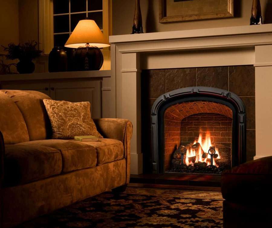 Sala de estar acogedora con chimenea brillando cálidamente junto a una alfombra estampada y sofá. — Fuego acogedor Fondos de pantalla