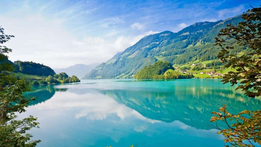 Turquoise lake reflecting mountains and sky framed by trees — Full HD Background