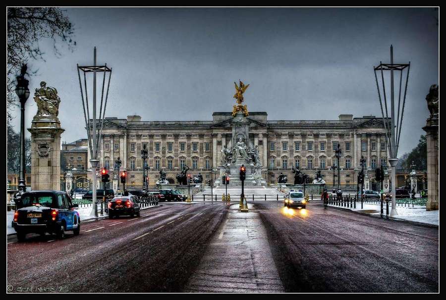 Palácio de Buckingham visto de uma rua molhada de Londres com carros e estátuas sob um céu cinzento. — Fundo do Palácio de Buckingham Papéis de Parede