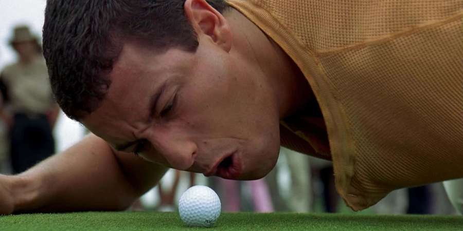 Golfer blowing a golf ball on green grass with intense focus. — Funny Golf Wallpaper