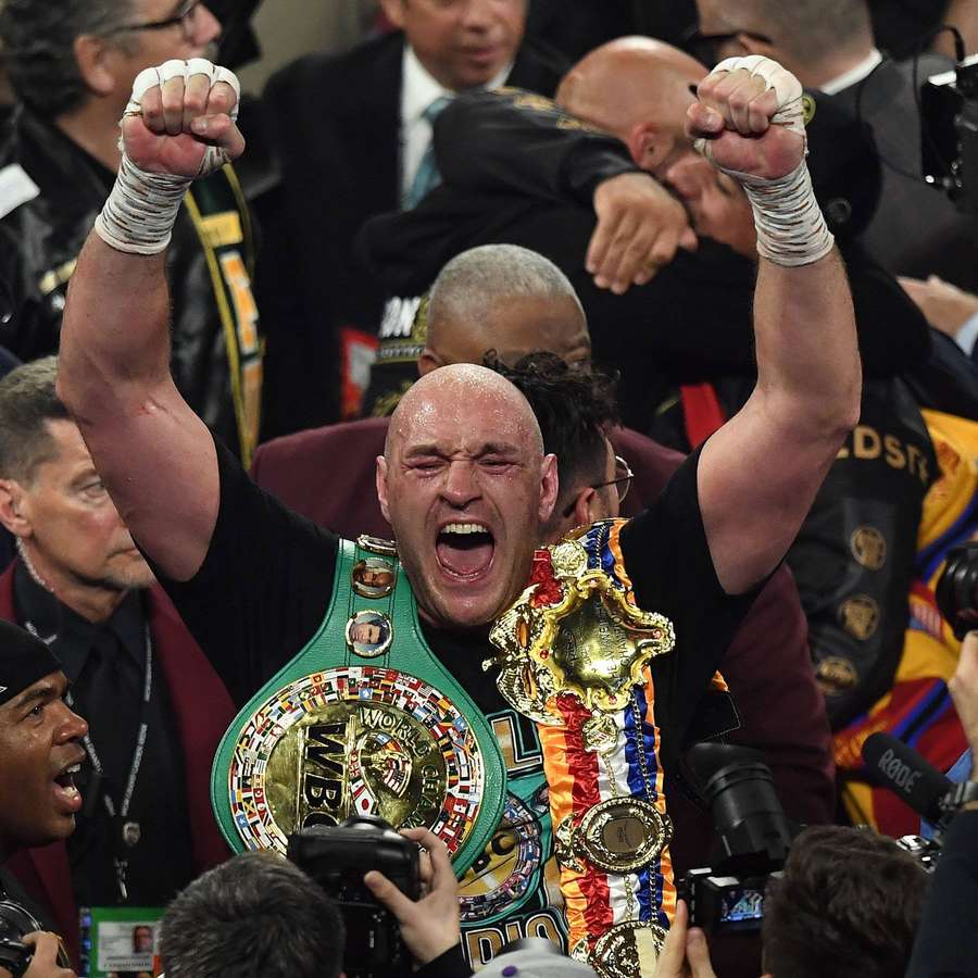 Boxer feiert Sieg mit erhobenen Fäusten und trägt Meisterschaftsgürtel. — Fury-bilder Hintergrund Wallpaper