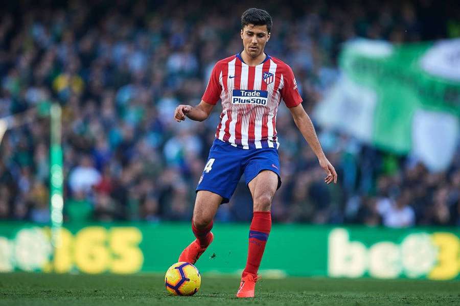 Jugador de fútbol driblando el balón en el campo de césped durante el partido con espectadores al fondo. — Futbolista Imágenes