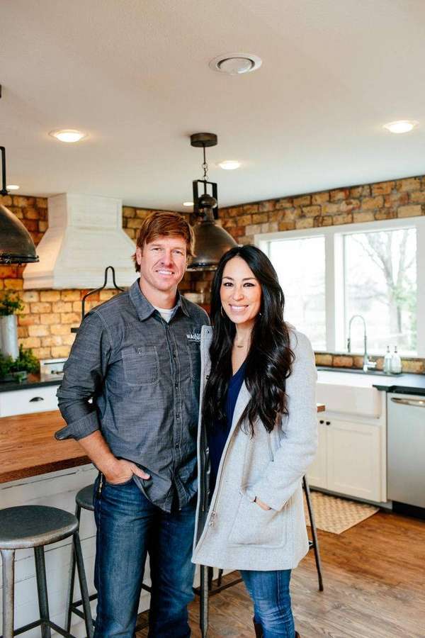 A happy couple posing in a stylish kitchen with brick walls and wooden counters. — Gaines Wallpaper