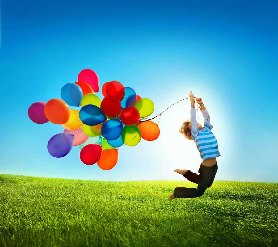 Niño saltando con globos de colores en un campo de hierba soleado. — Galaxy Tab Fondos de pantalla