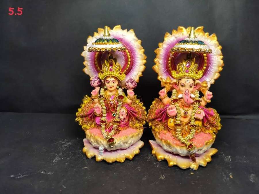 Two colorful Hindu deity statues with gold crowns and pink halos on a dark surface. — Ganesh Lakshmi Wallpaper