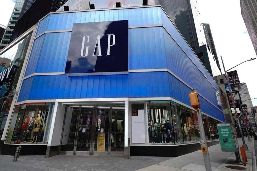 Ein blaues GAP-Geschäft an einer Ecke mit Schaufensterpuppen in den Fenstern und Fußgängern auf dem Bürgersteig. — Gap Bilder