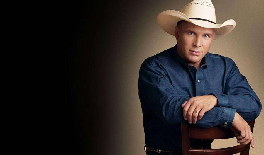 Man in cowboy hat and denim shirt leaning on wooden chair in studio — Garth brooks Background