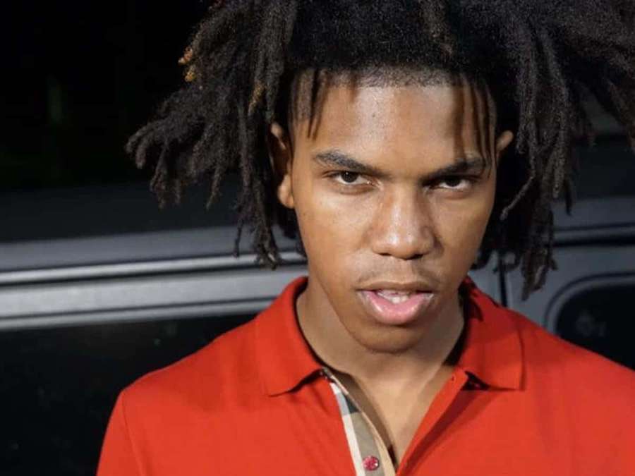 Young man with dreadlocks in red shirt looking intensely at camera at night. — Gee Money Wallpaper