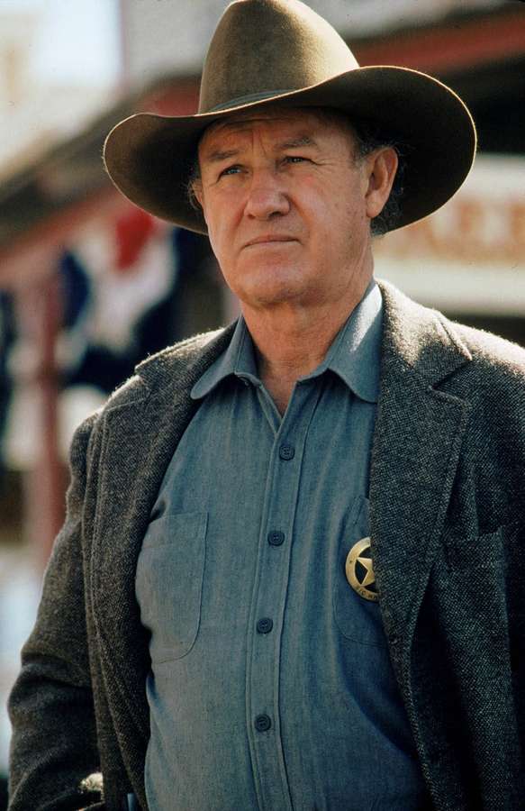 Ein streng blickender Cowboy-Sheriff mit Hut und Abzeichen. — Gene Hackman Bilder