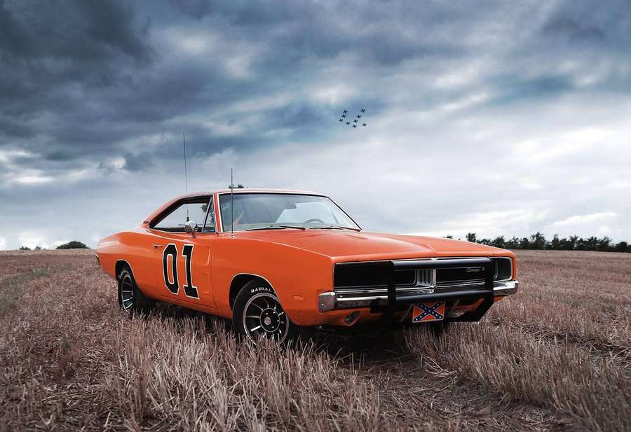 Muscle car clásico naranja en un campo seco bajo cielo tormentoso con aviones volando sobre él. — General Lee Fondos de pantalla