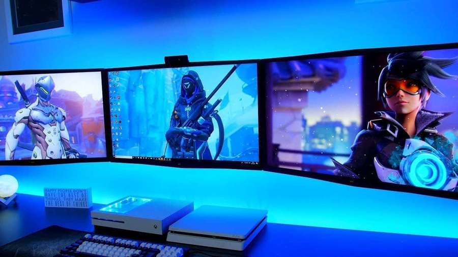 Gaming-Setup mit drei gebogenen Monitoren, die Overwatch-Charaktere unter blauer Beleuchtung zeigen. — Genji Bilder