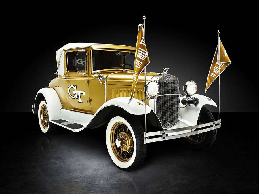 Goldener Vintage-GT-Wagen mit Flaggen im Studiolicht — Georgia Tech Bilder