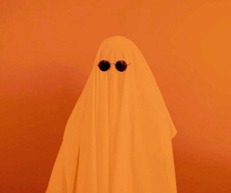 A ghost wearing sunglasses against an orange background. — Ghost Aesthetic Background