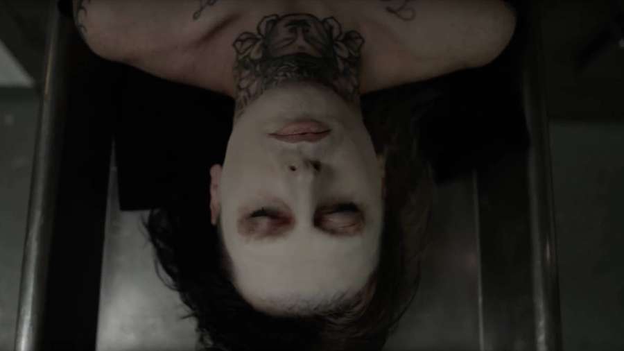 Person mit weißer Gesichtsbemalung und Hals-Tattoo, kopfüber in metallischer Struktur liegend. — Ghostemane Hintergrundbild