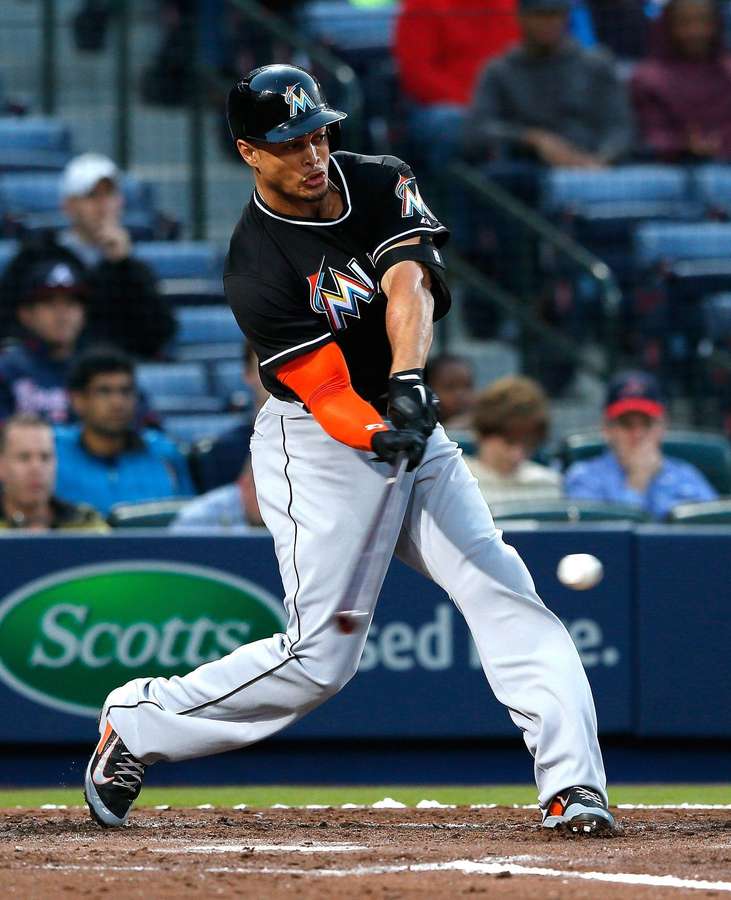 Baseball-pelaaja heilauttaa mailaa palloa kohti yöpelissä. — Giancarlo Stanton Taustakuvat