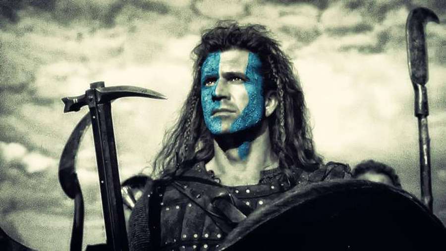 Warrior with blue face paint holding weapons under cloudy sky — Gibson Wallpaper