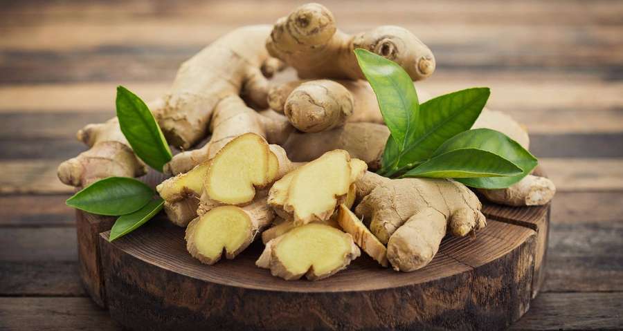 Fresh ginger root and slices with green leaves on wooden board. — Ginger Wallpaper