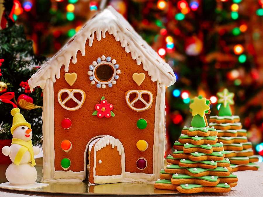 Gingerbread house with candy decorations and cookie trees near a snowman. — Gingerbread house Wallpaper