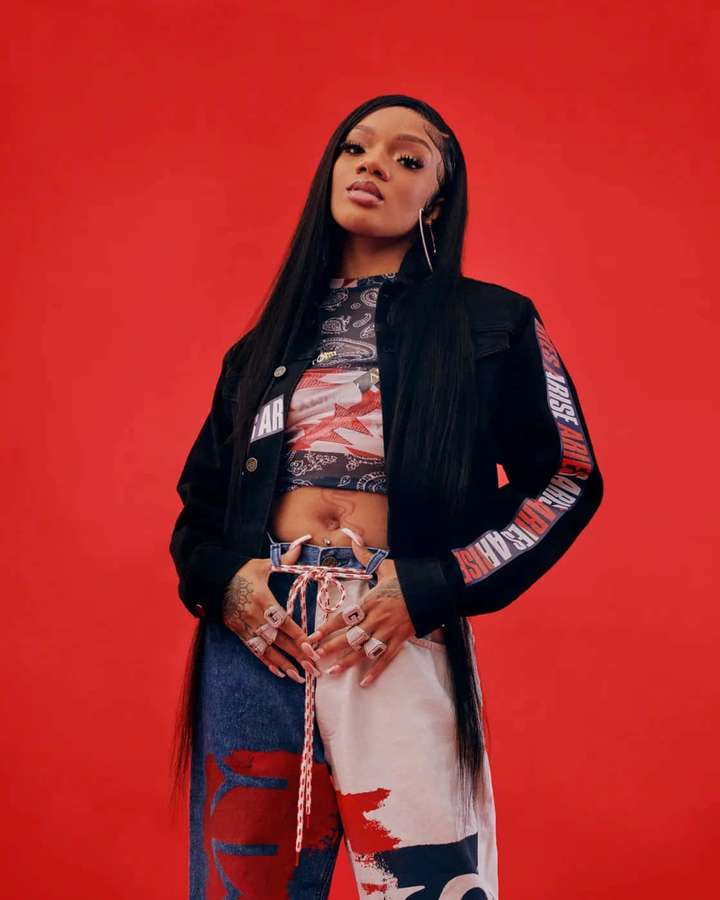 A stylish woman in streetwear poses against a red background. — Glorilla Picture