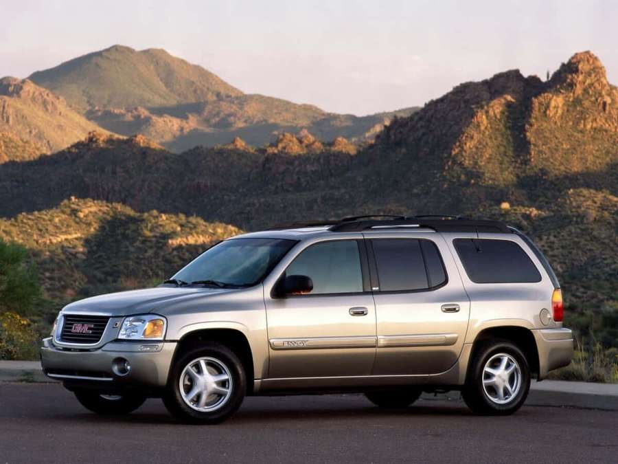 Silver GMC Envoy SUV parked near mountains at sunset. — Gmc Envoy Wallpaper