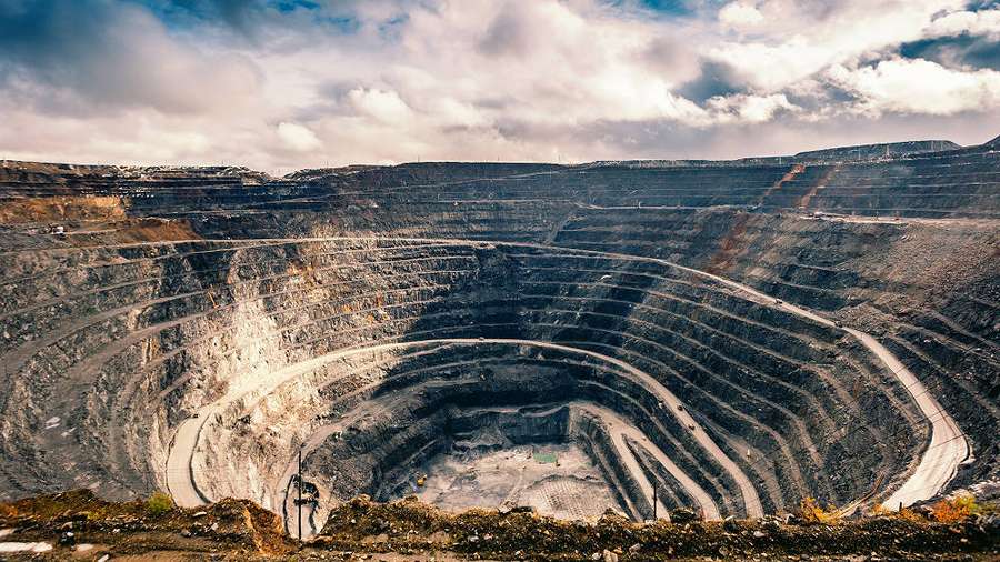 Large open-pit mine with terraced rock walls under a cloudy sky. — Goldmines Wallpaper