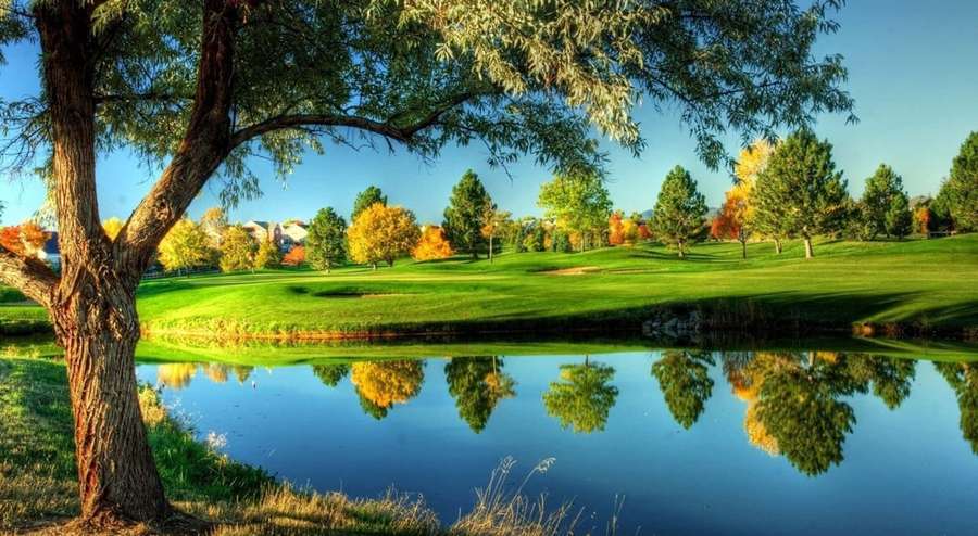 Campo de golfe no outono com árvores refletidas em um lago sob um céu azul claro. — Golfe incrível Papéis de Parede