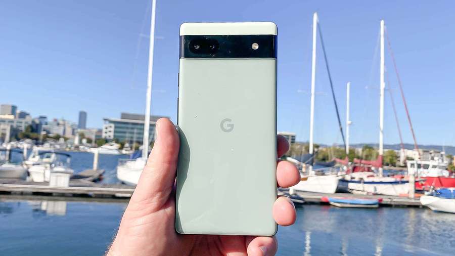 Hand holding a green Google Pixel phone at a marina with boats and city buildings. — Google Pixel 3 Background